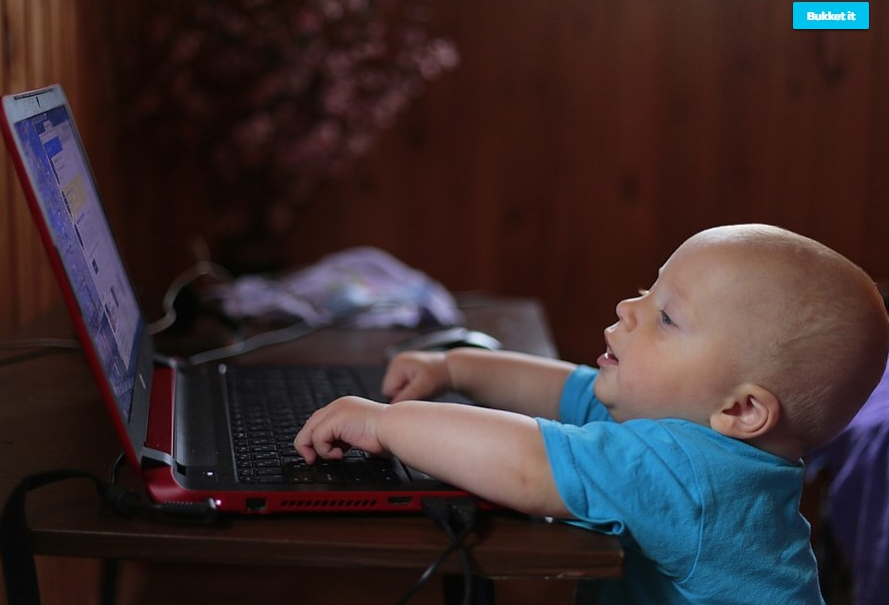 a toddler reaching for a laptop